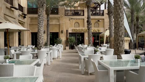 Leere-Stühle-Und-Tische-Von-Bars-Und-Restaurants-Unter-Palmen-Im-Madinat-Jumeirah-Resort-In-Dubai,-Vereinigte-Arabische-Emirate