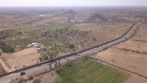Truck-Driving-On-The-Asphalt-Road-Between-Barren-Lands-In-Rajasthan,-India---aerial