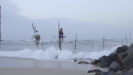 Hombres-De-Sri-Lanka---Pescadores-Sobre-Zancos-Pescando-En-La-Costa-De-Weligama-En-Un-Día-Sombrío-En-Matara,-Sri-Lanka