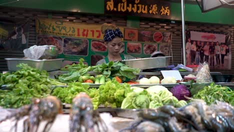 Eine-Marktverkäuferin,-Die-Meeresfrüchte-Und-Gemüse-In-Chinatown-In-Bangkok,-Thailand,-Verkauft-–-Mittlere-Aufnahme,-Schwenk-Rechts