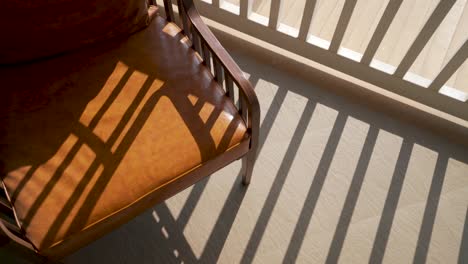 Brown-Leather-Chair-In-The-Balcony-Of-A-House-With-White-Railings-On-A-Sunny-Day---top-orbiting-shot