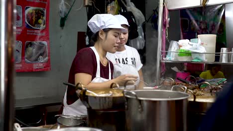 Schöne-Thailändische-Frau-Serviert-Heiße-Suppe-In-Einem-Imbissstand-In-Chinatown,-Bangkok,-Thailand---Nahaufnahme