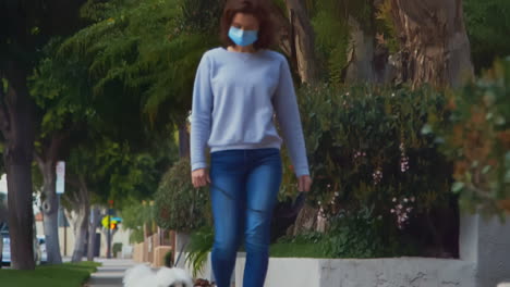 [Camera-Used:-Canon-C300]-Caucasian-woman-wearing-a-surgical-face-mask-while-outside-walking-her-dog