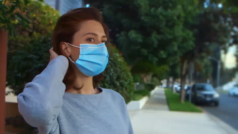 [Camera-Used:-Canon-C300]-Caucasian-woman-outside-wearing-a-surgical-face-mask-and-fixing-her-hair