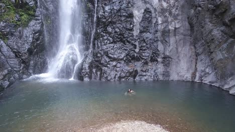 Lone-Woman-Swimming-At-Mainapi-Waterfall-In-Netravali-Wildlife-Sanctuary,-South-Goa,-India
