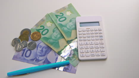 Una-Panorámica-Lenta-Que-Muestra-50-Dólares-Canadienses-Y-Cambio,-Junto-A-Una-Calculadora-Y-Un-Bolígrafo