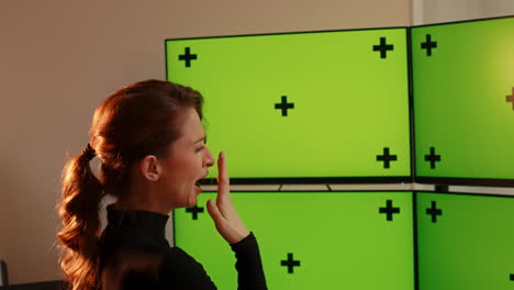 -Young-caucasian-woman,-multiple-green-screen-computer-monitors-with-tracking