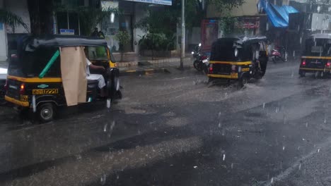 Tuk-Tuk-Vehicles-Travelling-On-The-Asphalt-Street-In-Mumbai,-India-On-A-Rainy-Day---wide-slowmo-shot