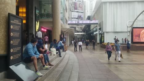 People-Sitting-On-The-Staircase-At-The-Entrance-Of-A-Shopping-Mall-In-Mumbai,-India---long-slowmo-shot