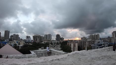 Gente-En-La-Azotea-De-Un-Edificio-Viendo-Las-Gruesas-Nubes-Grises-Que-Se-Elevan-Sobre-El-Horizonte-De-Mumbai-Durante-El-Amanecer-En-La-India---Timelapse
