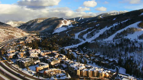 Aerial-Cinematic-Drone-i70-cars-on-highway-at-Vail-Village-Vail-ski-resort-late-afternoon-sunset-of-ski-trails-and-gondola-scenic-mountain-landscape-of-Colorado-forward-pan-up-reveal-movement