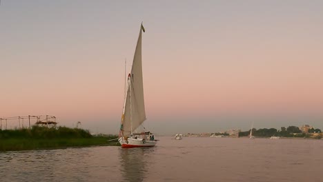 Wunderschöne-Flusslandschaft-Mit-Felukenbooten-Auf-Dem-Nil-In-Luxor-Mit-Den-Farben-Des-Sonnenuntergangs,-Die-Sich-Auf-Dem-Wasser-Spiegeln,-Ägypten