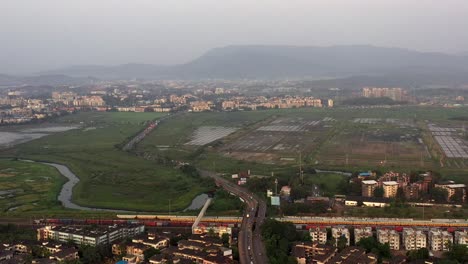 Panoramablick-Auf-Die-Stadtlandschaft-Mit-Gebäuden,-Autobahn-Und-Bahnhof-In-Vasai,-Mumbai,-Indien-–-Luftdrohnenaufnahme