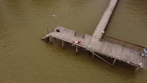 Man-Wearing-Swimsuit-Laying-Down-On-Wooden-Pier-In-Parana-River,-Argentina