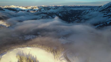Flying-Above-Light-Clouds-and-Snowy-Landscape-of-Teton-Pass,-Wyoming