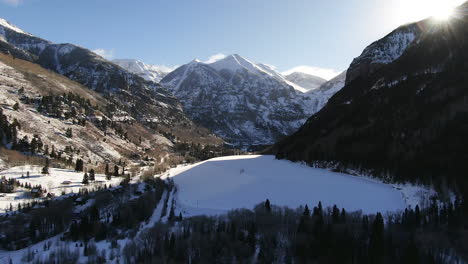 Aerial-Cinematic-Drone-from-above-view-of-Telluride-mountain-ski-resort-downtown-Colorado-of-scenic-mountains-landscape-and-historic-buildings-early-sun-light-mid-winter-pan-forward-reveal-movement