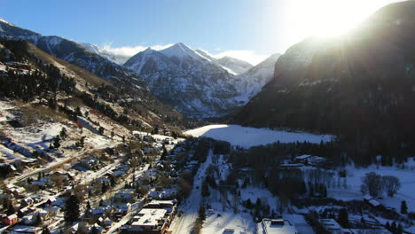 Aerial-Cinematic-Drone-view-of-Telluride-mountain-ski-resort-downtown-Colorado-of-scenic-mountains-landscape,-lake-and-historic-buildings-early-sun-light-mid-winter-forward-movement