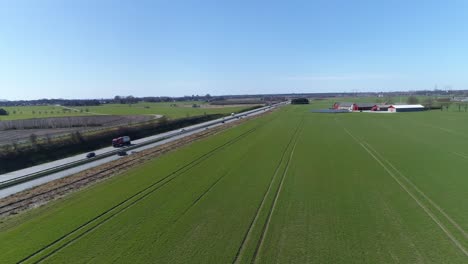 Tractor-farm-machinery-tracks-in-open-green-fields-along-E6-highway-sweden