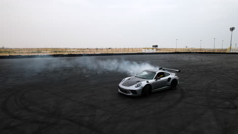 Aerial-tracking-shot-of-a-luxury-sports-car-being-drifted-creating-a-cloud-of-smoke