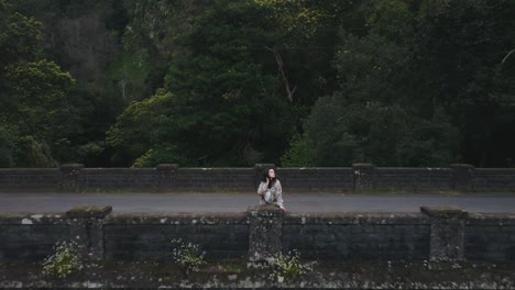 Drone-view-of-beautiful-woman-standing-on-old-bridge-in-Madeira-island,-Portugal