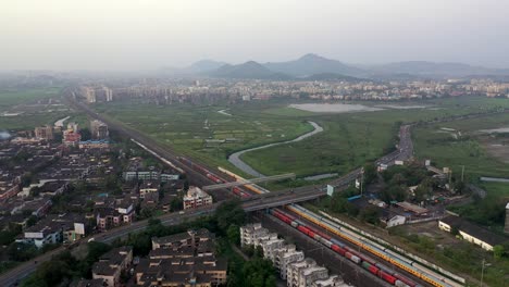 Suburban-Scene-with-Buildings,-Railway-Station-and-Bridge-in-Vasai,-Mumbai,-India---aerial-drone-shot