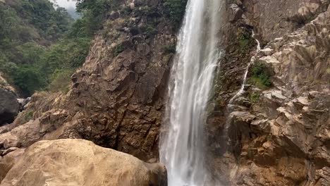 Rainbow-Falls-Cascading-On-Rugged-Cliff-In-Cherrapunji,-Meghalaya,-India---tilt-down-shot