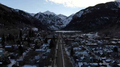 Aerial-Cinematic-Drone-view-of-Telluride-mountain-ski-resort-downtown-Colorado-of-scenic-mountains-landscape-and-historic-buildings-with-cars-and-trucks-early-sunrise-mid-winter-forward-movement