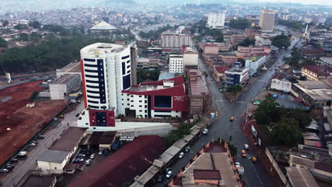 Aerial-view-away-from-the-General-Delegation-Of-Taxes-building,-in-cloudy-Yaounde,-Cameroon---pull-back,-drone-shot