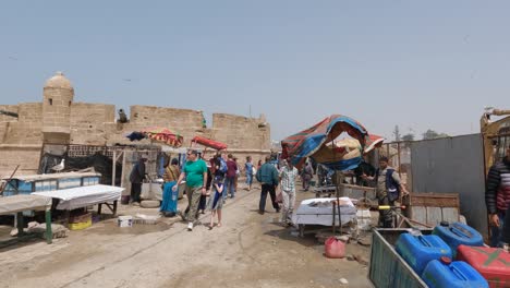 Touristen-Und-Einheimische-Am-Hafen-Von-Essaouira-Mit-Einem-Jungen-Mädchen,-Das-Sich-Beim-Gehen-Die-Nase-Hält