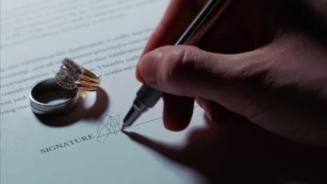 -Close-up-low-angle-shot-of-a-female-caucasian-hand-signing-a-document,-with-wedding-rings
