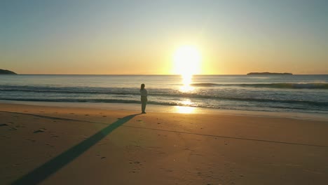 Woman-silhouette-stands-alone-at-the-beach-contemplating-the-ocean