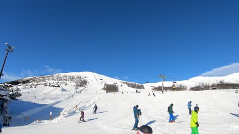 Skiers-at-Myrkdalen-Ski-Resort,-Norway-ski-towards-bottom-of-hill,-towards-camera