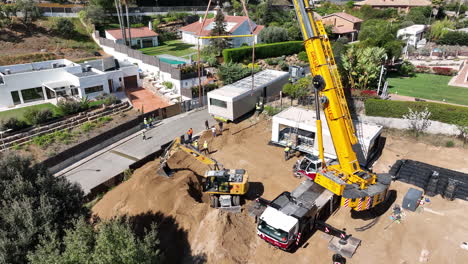 Vista-Aérea-Sobre-El-Remolque-Que-Entrega-La-Propiedad-De-Casa-Modular-A-La-Soleada-Parcela-De-Construcción