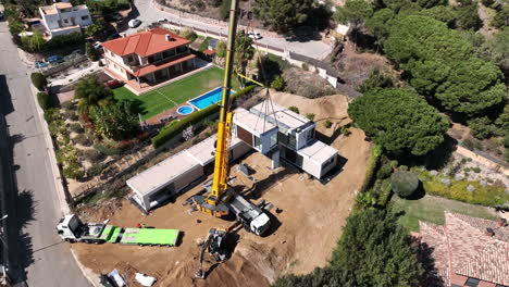 Aerial-view-of-construction-crane-lifting-modular-property-project-onto-foundation-building