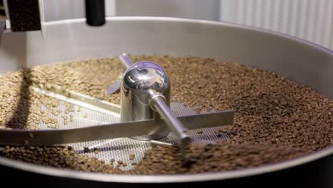 Die-Silberne-Trommelmaschine-Dreht-Sich-Und-Verteilt-Die-Kaffeebohnen,-Um-Sie-Gleichmäßig-Zu-Rösten