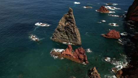 Aerial-view-across-Ponta-de-São-Lourenço-red-volcanic-rocky-formations-surrounded-by-Madeira-shimmering-sunlit-ocean-seascape