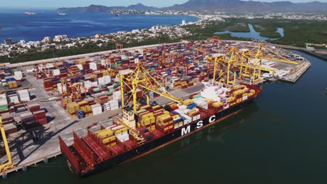 Container-Cargo-Freight-Ship-During-Discharging-At-Manzanillo-Port-In-Colima,-Mexico---aerial-drone-shot