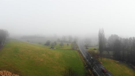 Drone-Volando-Sobre-El-Campo-Agrícola-Al-Lado-De-La-Carretera-Cerca-De-Odenwald-En-Un-Día-De-Niebla,-Hesse-Alemania