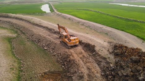 Excavator-on-a-dirt-road-in-a-farmland