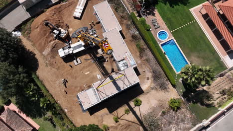 Aerial-view-circling-above-heavy-crane-lift-installing-smart-modular-housing-on-construction-site