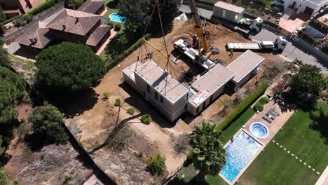 Aerial-view-construction-site-crane-lifting-smart-modular-housing-development-onto-foundation-building