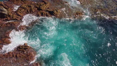 Aerial-flyover-rocky-colorful-coast-in-Tenerife-with-waves-crashing,-dolly-in