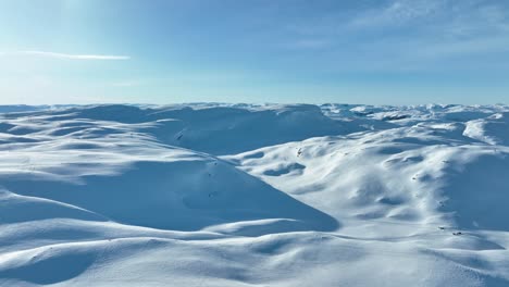 Heavy-snowpack-on-Vikafjell-Mountain-Norway,-good-for-hydroelectric-electricity-production---Masts-with-powerlines-passing-on-ridge-in-middle-of-frame