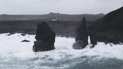 Aerial-Shot-of-Iceland-seashore-waves-through-cliffs-and-people-watching-the-horizon-on-a-foggy-day