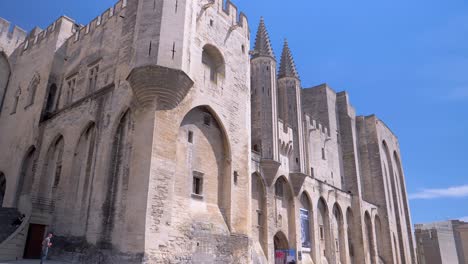 Fachada-De-Un-Gran-Castillo-De-Piedras-Claras-Con-Torres,-Arcos,-Ventanas-Pequeñas,-Un-Cielo-Azul-Con-Un-Clima-Soleado