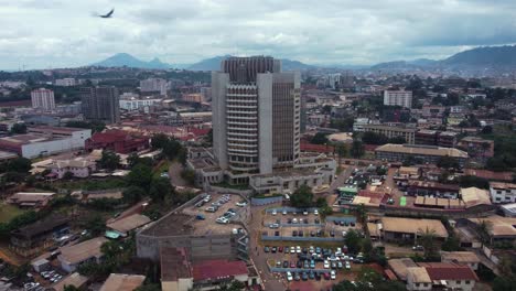 Static-aerial-view-of-birds-flying-in-front-of-the-BEAC-building-in-Yaounde,-Cameroon
