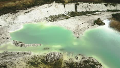 Aerial-shot-of-abandoned-kaolin-quarry-with-turquoise-lake-water,-circular-drone-flight