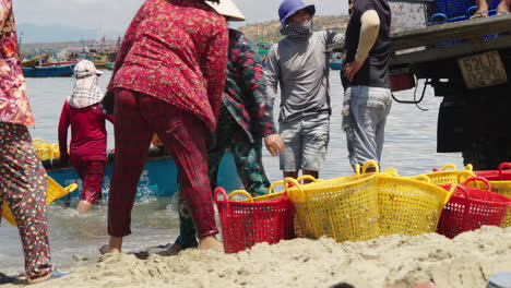 Las-Mujeres-Locales-Descargan-Cestas-Llenas-De-Pescado-Fresco-En-La-Playa-De-Mui-Ne.