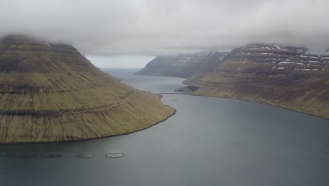 Aerial-view-Kunoy-and-Haraldssund-fjord-on-Borðoy-island,-Faroe---dramatic-dark-clouds-flying-in-the-air