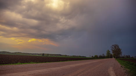 Thunderstorm-clouds-covering-golden-sunshine-above-agriculture-landscape,-time-lapse